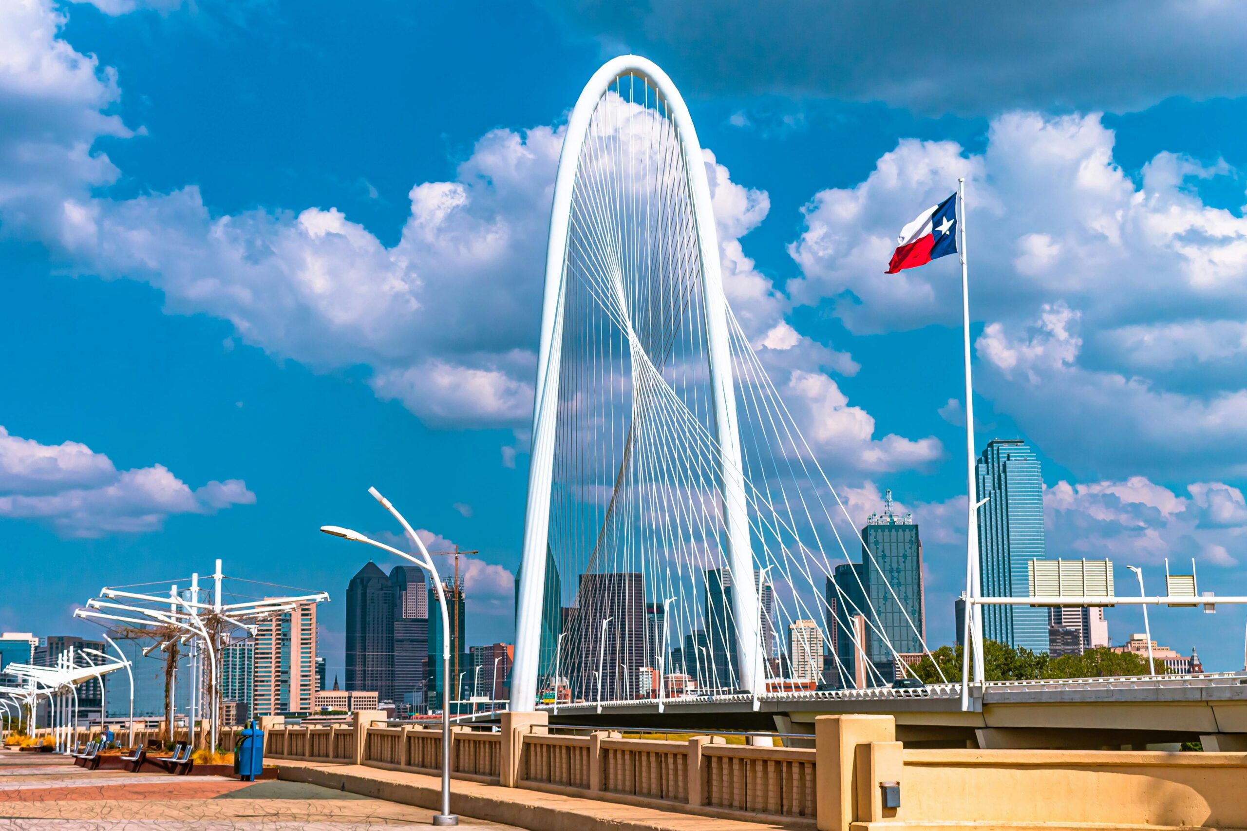Home The iconic Margaret Hunt Hill Bridge in Dallas, Texas under a bright blue sky with clouds.