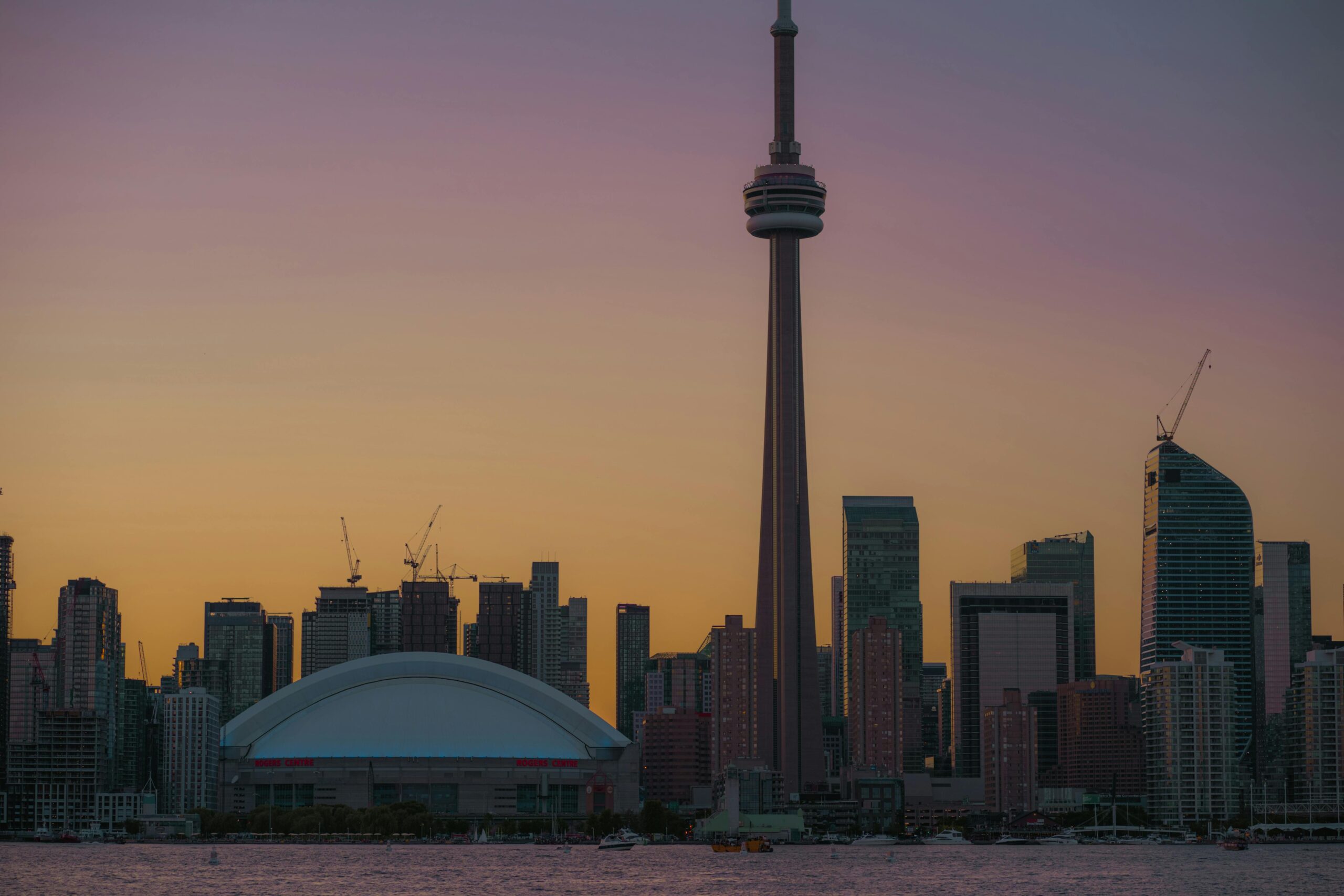 Home Stunning Toronto skyline during sunset, highlighting the iconic CN Tower against a vibrant sky.