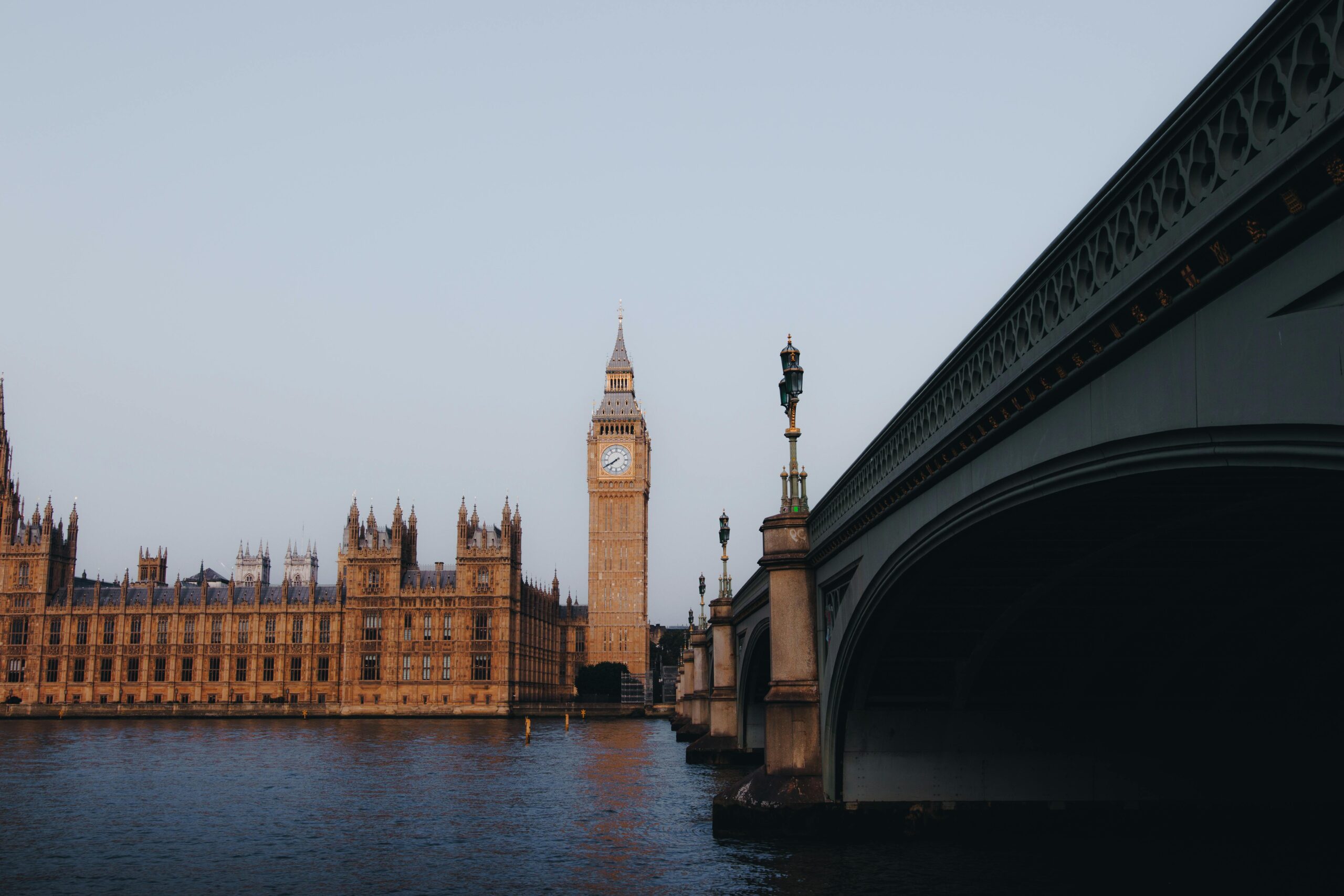 Home Iconic view of Big Ben and Westminster Bridge over the Thames River in London, England during the daytime.